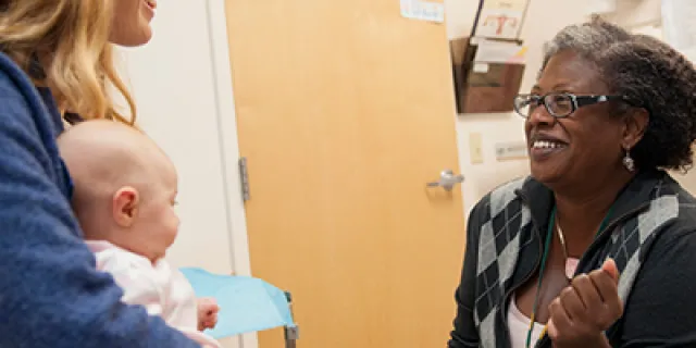 Female doctor talking with female patient and her baby. 